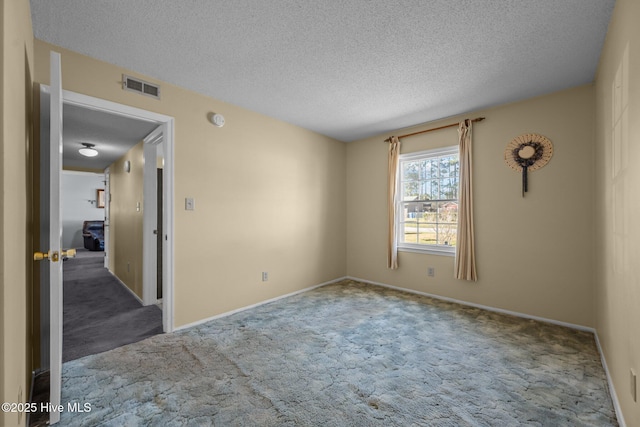 unfurnished room with visible vents, carpet, and a textured ceiling