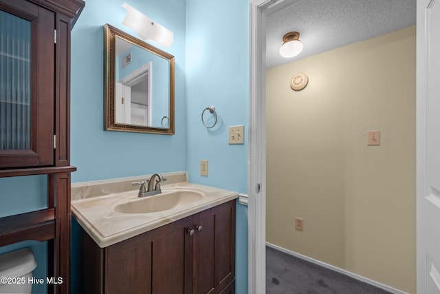 bathroom with visible vents, a textured ceiling, vanity, and baseboards