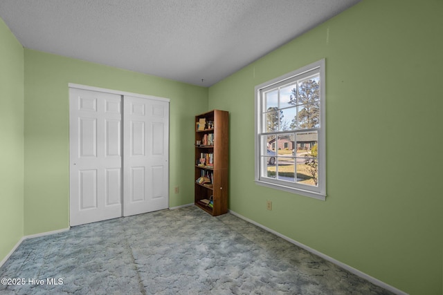 unfurnished bedroom with a closet, baseboards, a textured ceiling, and carpet