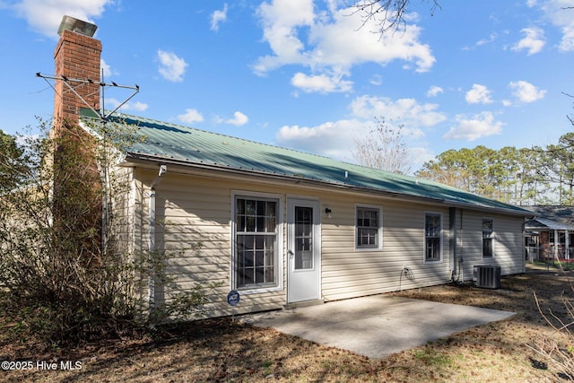 rear view of house featuring metal roof, a patio, central AC unit, and a chimney