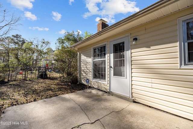 doorway to property with a chimney, a patio, and fence