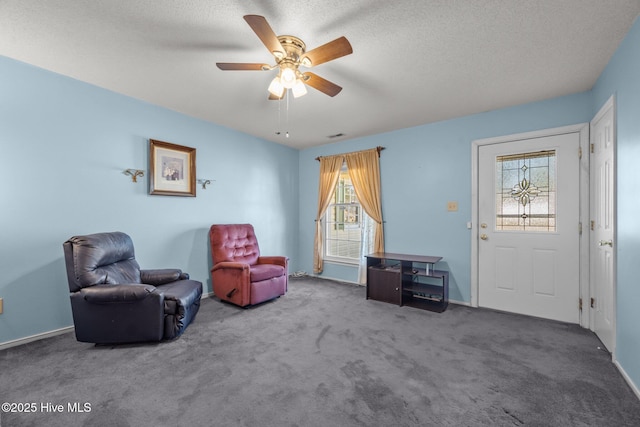 living area with baseboards, a textured ceiling, ceiling fan, and carpet flooring