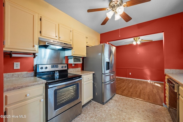 kitchen featuring baseboards, ceiling fan, under cabinet range hood, light countertops, and appliances with stainless steel finishes