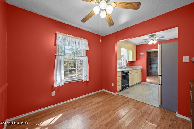 kitchen featuring baseboards, freestanding refrigerator, ceiling fan, light wood-style floors, and dishwasher