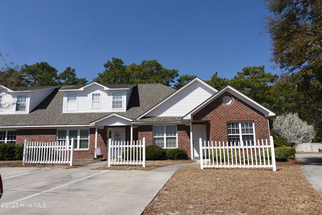 view of front facade featuring brick siding and a fenced front yard