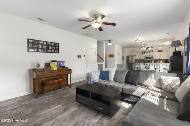 living room with visible vents, a ceiling fan, stairway, baseboards, and dark wood-style flooring
