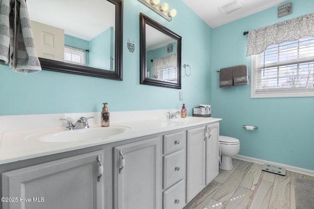 full bathroom with a sink, baseboards, toilet, and double vanity