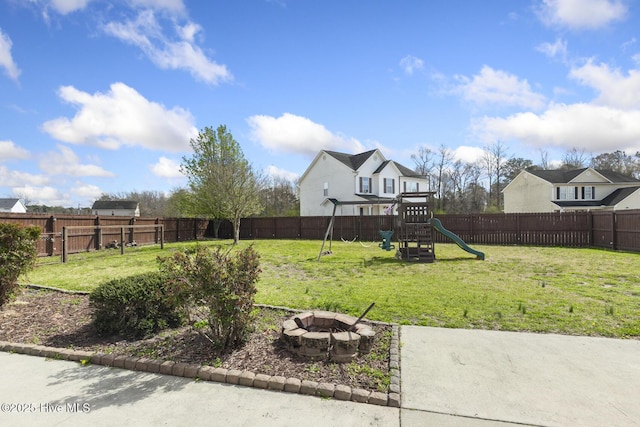 view of yard with a playground, a fenced backyard, and an outdoor fire pit