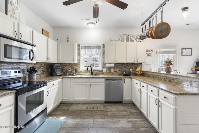 kitchen with visible vents, a ceiling fan, a sink, appliances with stainless steel finishes, and decorative backsplash