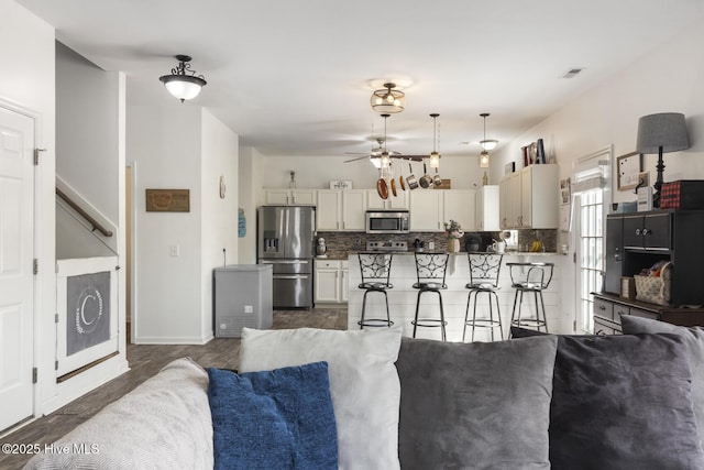 kitchen with a ceiling fan, open floor plan, backsplash, and stainless steel appliances