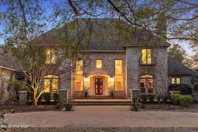 french country home with brick siding and roof with shingles
