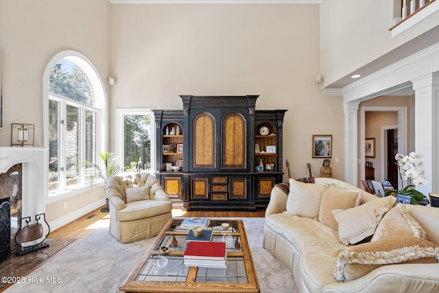living area featuring wood finished floors, baseboards, decorative columns, and a towering ceiling