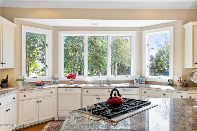 kitchen with a sink, light stone countertops, crown molding, stainless steel gas cooktop, and paneled dishwasher