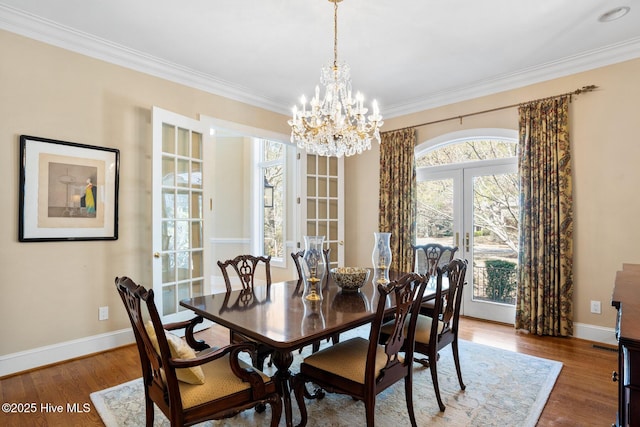 dining area featuring french doors, wood finished floors, a notable chandelier, and ornamental molding