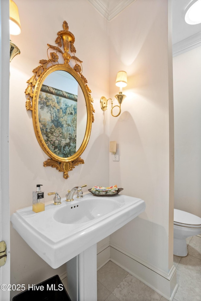 half bathroom featuring tile patterned floors, baseboards, ornamental molding, and toilet