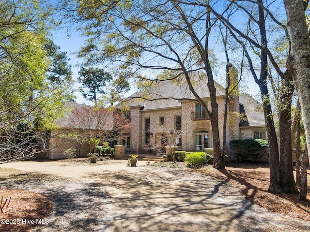 french country style house with a chimney and brick siding