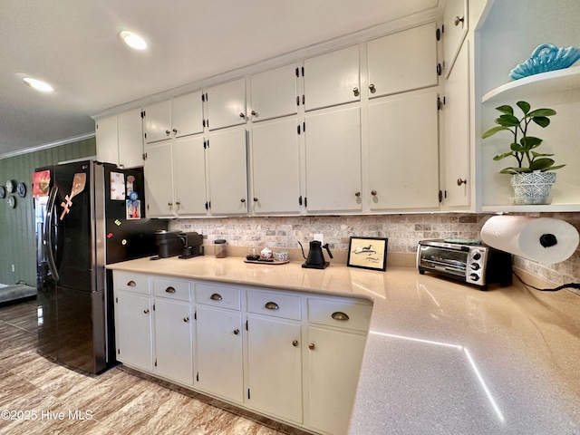 kitchen featuring backsplash, freestanding refrigerator, light countertops, and white cabinets