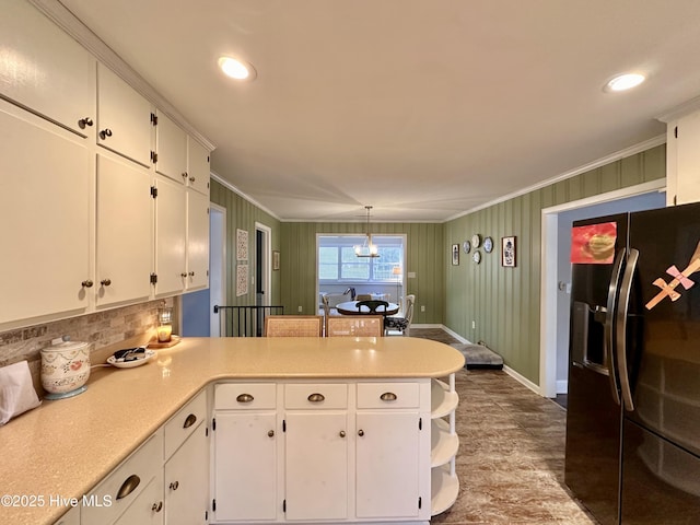 kitchen featuring a peninsula, backsplash, white cabinetry, black refrigerator with ice dispenser, and crown molding