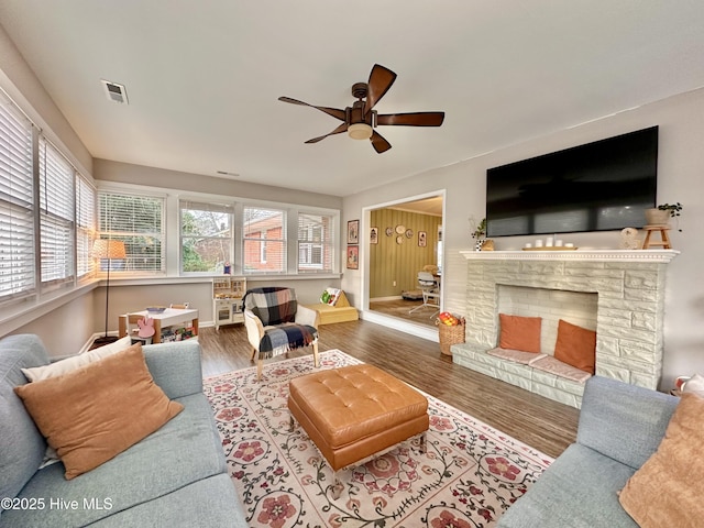 living room featuring wood finished floors, visible vents, a ceiling fan, and baseboards