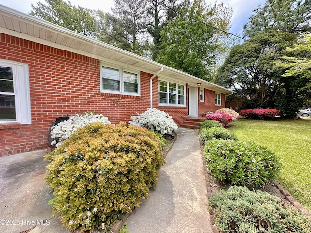 doorway to property with brick siding and a yard