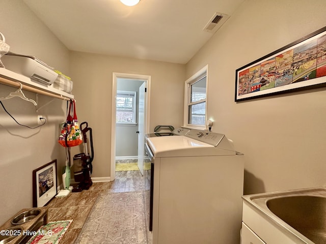 washroom featuring a sink, baseboards, visible vents, separate washer and dryer, and laundry area
