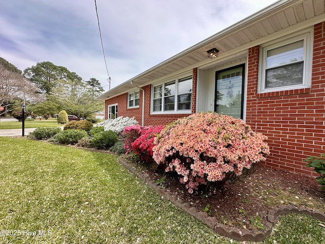 view of side of home with brick siding and a yard