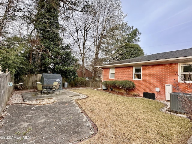 view of yard with a fenced backyard, central AC, and a patio