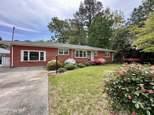 single story home featuring brick siding, a front yard, and concrete driveway