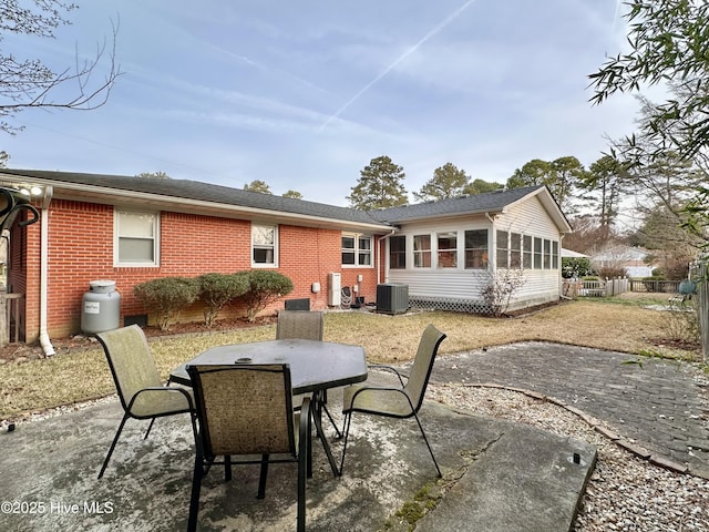 rear view of property featuring outdoor dining area, brick siding, and a patio