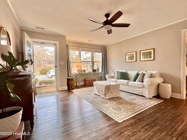 living area with baseboards, visible vents, a ceiling fan, dark wood-type flooring, and ornamental molding