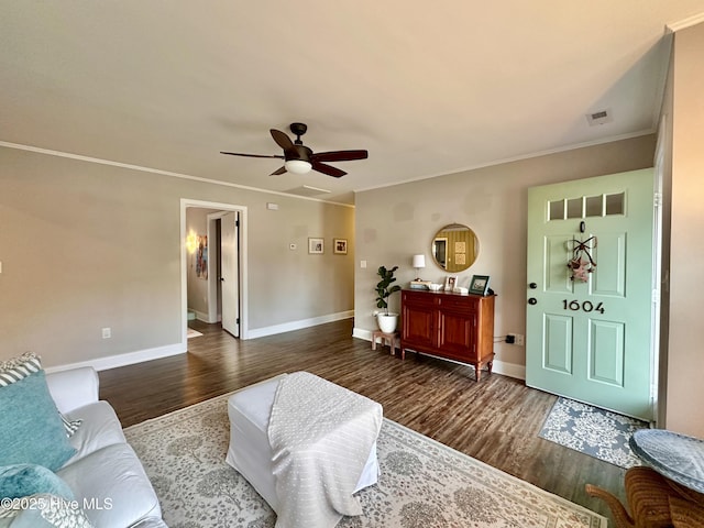 living area with wood finished floors, ceiling fan, baseboards, ornamental molding, and visible vents