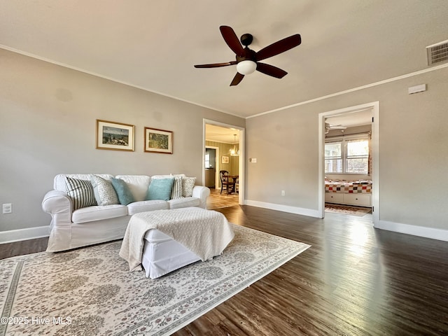 living area featuring baseboards, visible vents, ceiling fan, and crown molding
