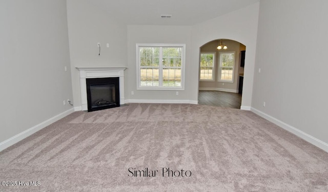 761 Regiment Rd, Jacksonville, NC 28546 - unfurnished living room with a fireplace with flush hearth, baseboards, carpet floors, arched walkways, and visible vents