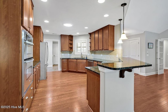 1061 Leesburg Dr, Leland, NC 28451 - kitchen featuring a peninsula, light wood-style flooring, stainless steel appliances, open shelves, and a breakfast bar area