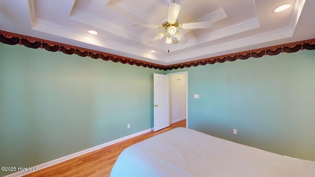 unfurnished bedroom featuring light wood finished floors, crown molding, and a raised ceiling
