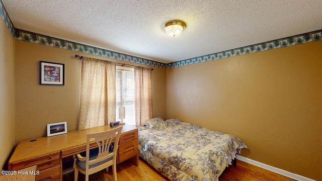 bedroom with baseboards, a textured ceiling, and wood finished floors
