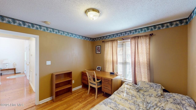 bedroom with a textured ceiling, light wood-type flooring, and baseboards