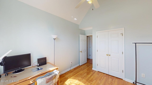 office featuring baseboards, a ceiling fan, light wood-style floors, and high vaulted ceiling