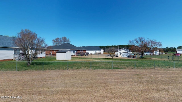 view of yard featuring a shed, an outdoor structure, and fence