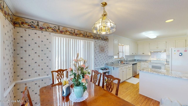 dining area with crown molding, wallpapered walls, light wood-style floors, and an inviting chandelier