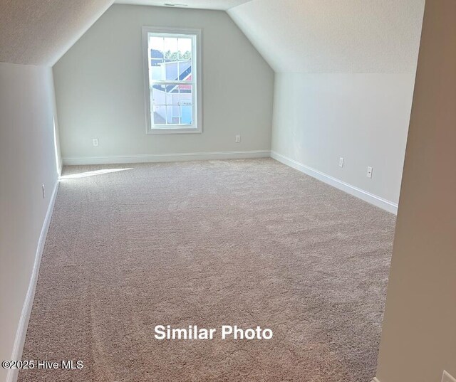 745 Secession Ln, Jacksonville, NC 28546 - additional living space with carpet flooring, baseboards, vaulted ceiling, and a textured ceiling