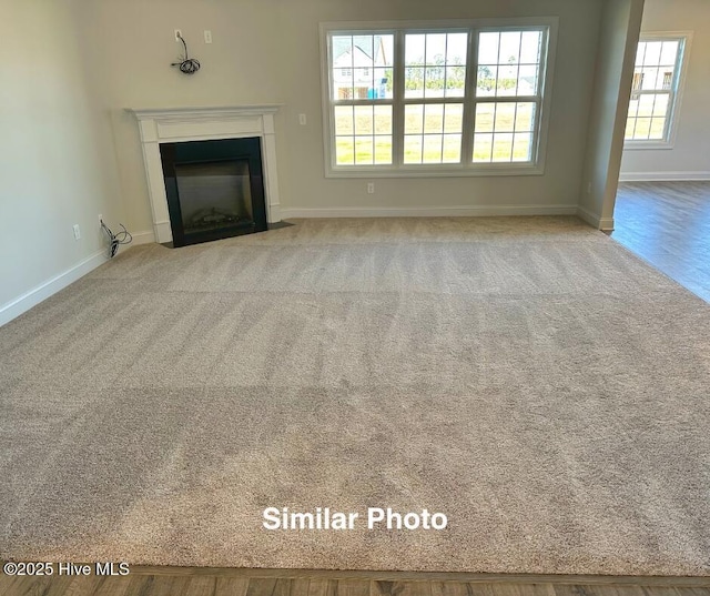745 Secession Ln, Jacksonville, NC 28546 - unfurnished living room featuring a fireplace with flush hearth, baseboards, and carpet floors