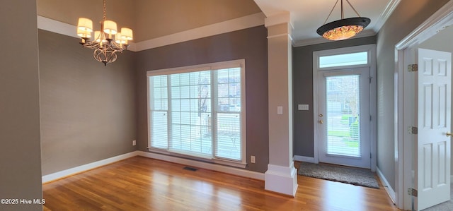 2429 Falls River Ave, Raleigh, NC 27614 - entryway featuring a chandelier, wood finished floors, plenty of natural light, crown molding, and ornate columns