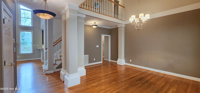 2429 Falls River Ave, Raleigh, NC 27614 - foyer entrance with a high ceiling, light wood-style flooring, decorative columns, a chandelier, and stairs