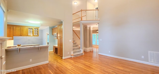 2429 Falls River Ave, Raleigh, NC 27614 - kitchen featuring light wood-type flooring, glass insert cabinets, a kitchen breakfast bar, crown molding, and a peninsula