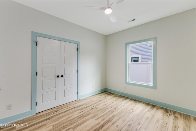 spare room featuring visible vents, light wood-type flooring, baseboards, and ceiling fan