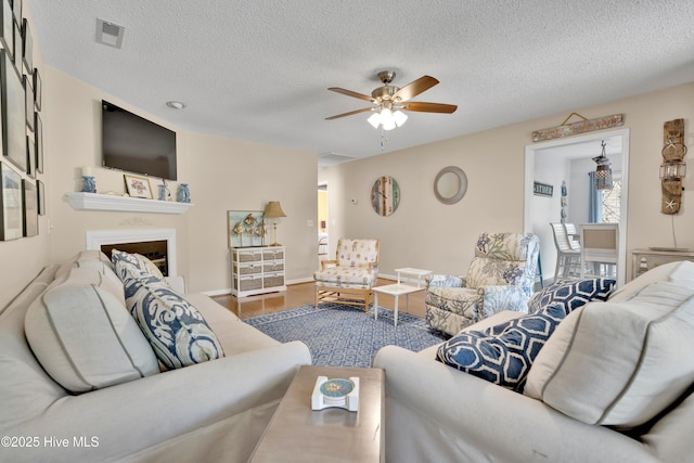 222 NE 36th St, Oak Island, NC 28465 - living room featuring a ceiling fan, visible vents, a textured ceiling, and a fireplace