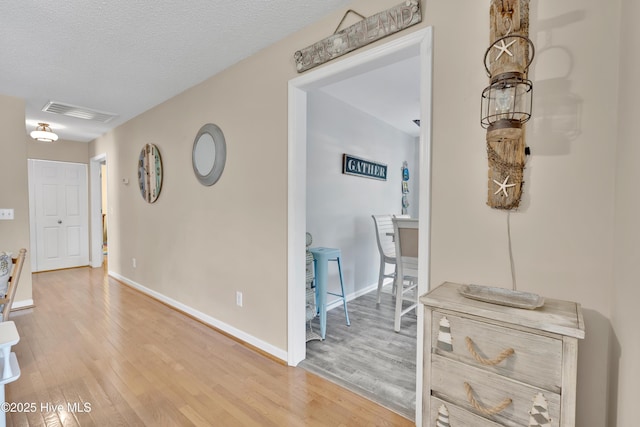 222 NE 36th St, Oak Island, NC 28465 - hallway featuring a textured ceiling, visible vents, light wood-type flooring, and baseboards