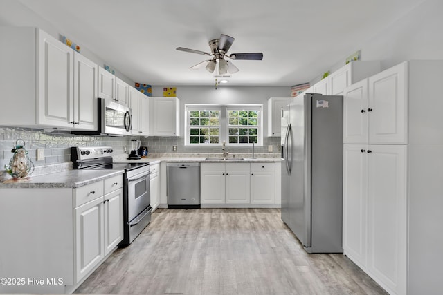 222 NE 36th St, Oak Island, NC 28465 - kitchen with a sink, stainless steel appliances, light wood-style floors, tasteful backsplash, and a ceiling fan