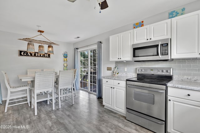 222 NE 36th St, Oak Island, NC 28465 - kitchen with light wood-type flooring, a ceiling fan, backsplash, and appliances with stainless steel finishes